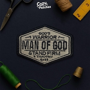 May include: Embroidered patch with the text "GOD'S WARRIOR MAN OF GOD STAND FIRM 1 TIMOTHY 6:11" in black and tan. The patch is in a hexagonal shape with a navy blue border. The brand name "Cozy Patches" is in the top right corner.