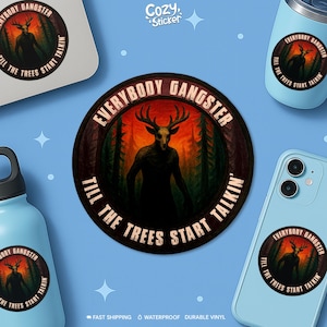 May include: A circular sticker with the text "EVERYBODY GANGSTER" and "TILL THE TREES START TALKIN" surrounds a dark illustration of a deer-like figure in a forest. The sticker is displayed on a laptop, phone, tumbler, and water bottle.