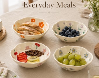 May include: Four cream-colored ceramic bowls with scalloped edges, each featuring different hand-painted floral and fruit motifs including orange flowers, purple tulips, red cherries, and blue blossoms, containing various food items.