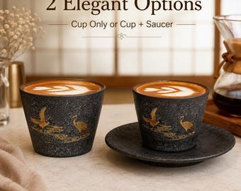 May include: Two dark gray speckled ceramic cups filled with coffee featuring latte art. One cup sits alone, while the other rests on a matching saucer. Both cups display gold crane illustrations. Text reads: 2 Elegant Options, Cup Only or Cup + Saucer.