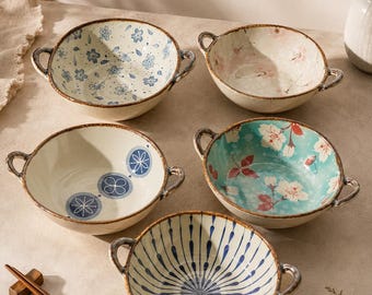 May include: Five ceramic bowls with two side handles, each featuring a unique pattern: blue floral, pink cherry blossom, blue circular motifs, teal floral, and blue radial stripes. The text "Choose Your Pattern" is printed above the bowls.