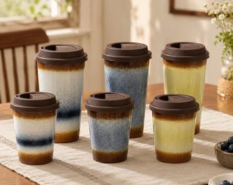 May include: A set of six ceramic travel mugs with dark brown lids, arranged in two rows. The mugs feature a reactive glaze finish in white, blue, and yellow, with a consistent dark brown base and rim color on each of the three distinct color styles.