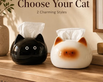 May include: Two cat-shaped tissue holders with white tissues emerging from the top. One is glossy black with white circular eyes, and the other is cream-colored with brown ear tips and a brown face patch. Text reads: Choose Your Cat 2 Charming Styles.