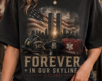 May include: A charcoal grey t-shirt featuring a graphic of the Twin Towers, an American flag, a firefighter helmet labeled 343, a police cap, and a medical bag. The text reads FOREVER IN OUR SKYLINE 9.11.2001 in a distressed, vintage-style font.
