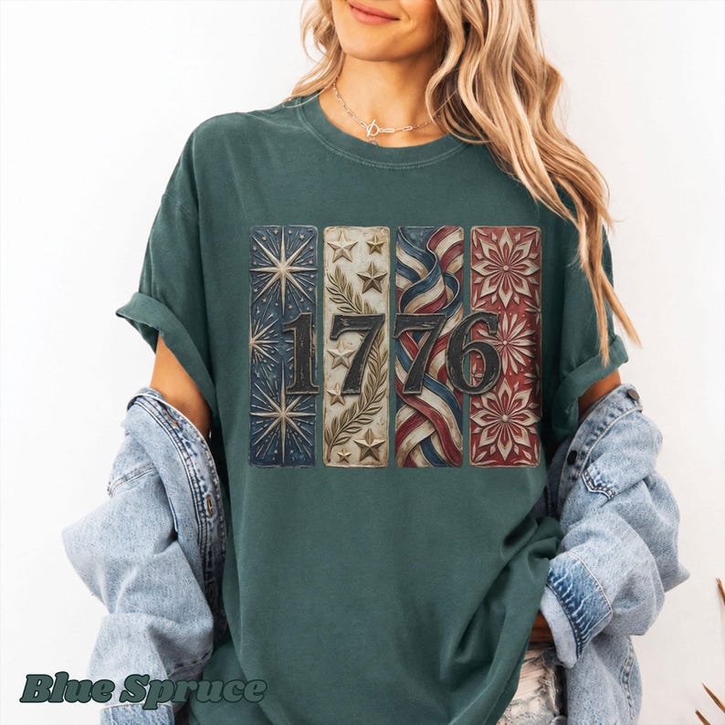 May include: A teal-colored t-shirt with the year "1776" displayed in a vintage, patriotic design. The graphic features stars, stripes, and floral elements in red, white, and blue, evoking a sense of American heritage and independence.