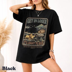 Op de afbeelding: Zwart T-shirt met een grafisch ontwerp met de tekst "GET IN LOSER IT'S ABOUT TO RAIN" en een illustratie van dieren en de ark van Noach. Het shirt heeft een relaxte pasvorm.