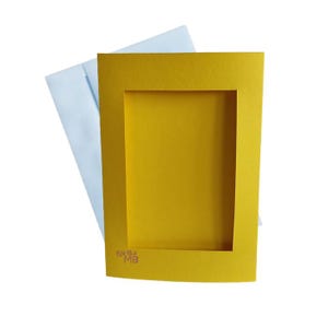 May include: A yellow card with a rectangular window cut out. The card has the text "kreikka MB" printed on the bottom.