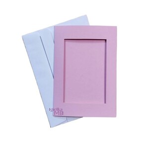 May include: A pink card with a white envelope. The card has a rectangular frame with a blank space inside. The card has the text "Igielka ME" printed on the bottom.