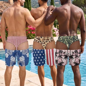 May include: Three pairs of swim trunks featuring trompe l'oeil designs. The first has red and white stripes above blue floral fabric. The second has a leopard print above an American flag pattern. The third has camouflage above a palm tree print.