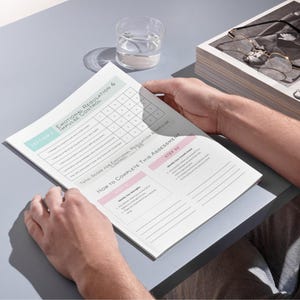 以下が含まれることがあります： 「感情調節と衝動制御」と題された印刷された評価フォームを人が持っています。フォームには採点用のグリッドと指示があります。背景には水を入れたグラスと書類の山があります。