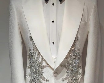 May include: A white tuxedo jacket with a black bow tie and a crystal embellishment design. The jacket has a satin lapel and a single button closure.