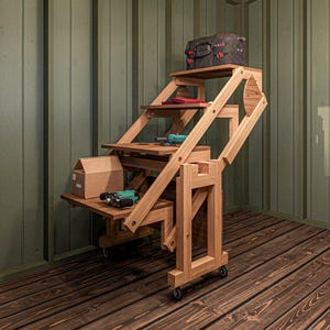 May include: A wooden folding table with wheels, featuring multiple shelves and a small box on the top shelf. The table is in a room with wood paneling on the walls.