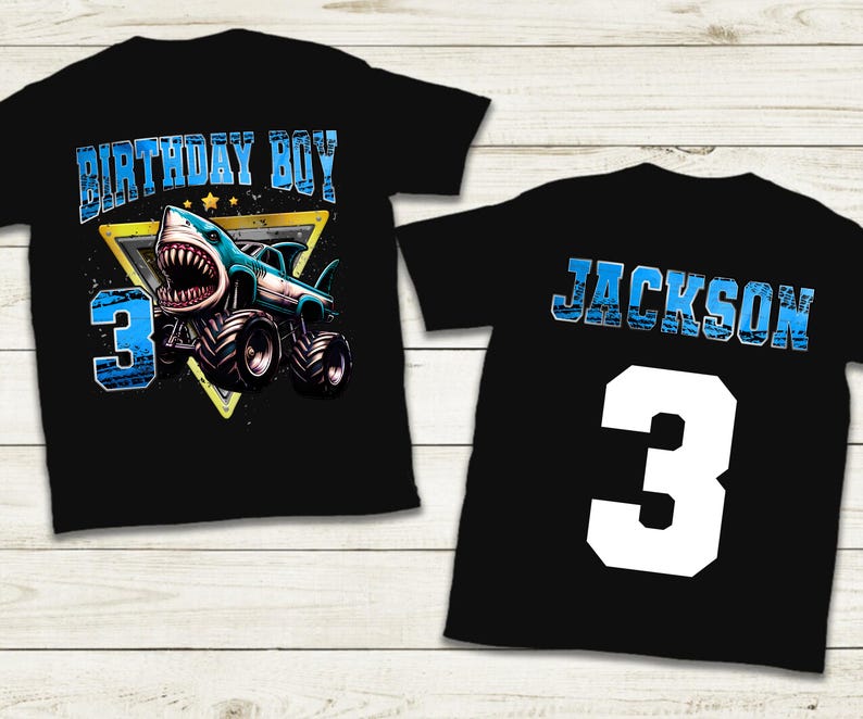 May include: Black t-shirts with a shark-themed design. One shirt features "BIRTHDAY BOY" and a shark monster truck with the number "3". The other shirt has the name "JACKSON" and the number "3".