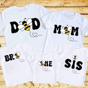 May include: White t-shirts with bee and word designs. The shirts say "Dad", "Mom", "Bro", "Sis", and "One".