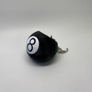 May include: A black and white 8-ball charm with a silver chain. The 8-ball is a popular symbol of luck and fortune.