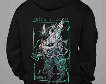 May include: Black hooded sweatshirt featuring a graphic of a character with a skull-like mask and the text "kafka hibino" and Japanese text. The design is outlined in teal. The sweatshirt is made of a soft material.