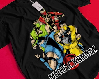 Könnte beinhalten: Schwarzes T-Shirt mit einer Grafik von vier Mortal Kombat-Charakteren in Rot, Grün, Gelb und Blau. Das Mortal Kombat-Logo ist in Weiß dargestellt. Ein weißes Etikett ist am T-Shirt befestigt.