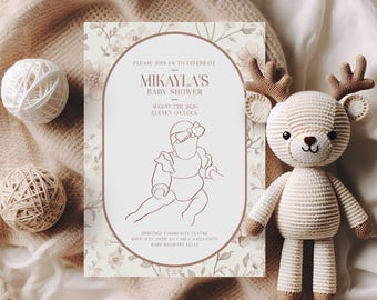 May include: A baby shower invitation with floral accents and the text "Mikayla's Baby Shower". A crocheted deer toy and two decorative yarn balls are also present. The invitation includes the date, time, and RSVP information.
