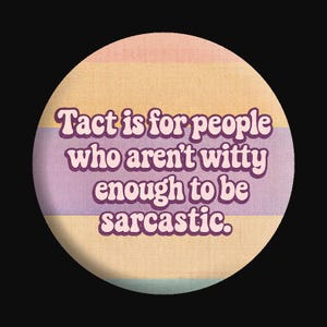 May include: Round button with a retro design. The button features a pastel color scheme with horizontal stripes in shades of pink, yellow, and blue. The text "Tact is for people who aren't witty enough to be sarcastic" is displayed in a purple font.