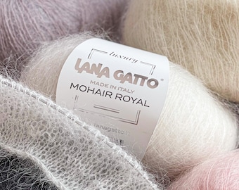 Puede incluir: Un primer plano de un ovillo de hilo de mohair blanco con una etiqueta que dice "Lana Gatto - Luxury - Made in Italy - Mohair Royal". El hilo es suave y esponjoso, y es perfecto para tejer o hacer ganchillo.