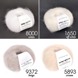 May include: Four balls of Lana Gatto Mohair Royal yarn in different colours: white, off white, beige, and cream. Each ball is labelled with the brand name, "Lana Gatto", and the yarn type, "Mohair Royal".