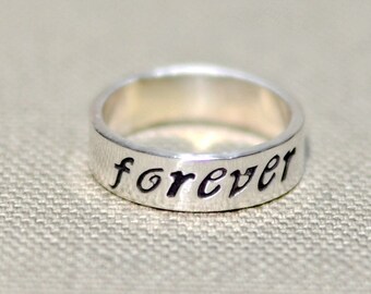 May include: A silver band ring with the word "forever" engraved on it.
