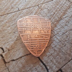 Copper guitar pick in shield shape with music notes - playable