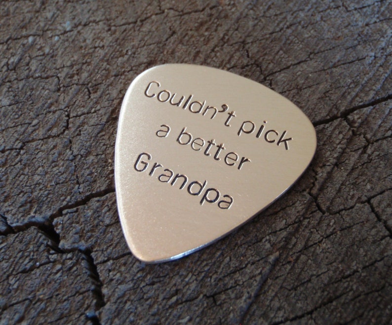 May include: Silver guitar pick with the text "Couldn't pick a better Grandpa" engraved on it.