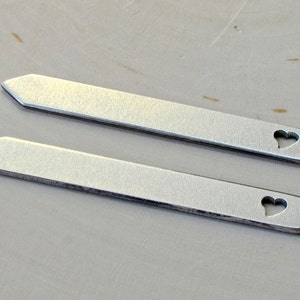 May include: Two silver metal tie bars with a heart-shaped cutout.