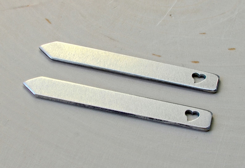 May include: Two silver metal tie bars with a heart-shaped cutout.