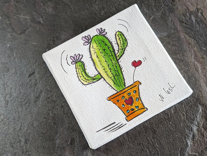 Puede incluir: Un lienzo pintado a mano con un cactus de dibujos animados con flores rosas y un coraz&oacute;n. El cactus est&aacute; en una maceta amarilla con detalles naranja y marr&oacute;n. El lienzo est&aacute; firmado "W. 165C".