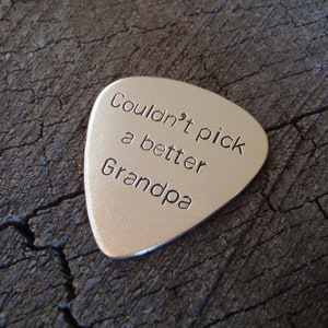 May include: Silver guitar pick with the text "Couldn't pick a better Grandpa" engraved on it.