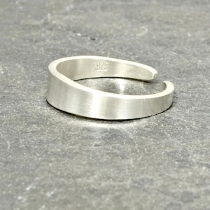 May include: A silver toe ring with a smooth, rounded surface. The ring is open on one side and has the number "925" stamped on the inside.
