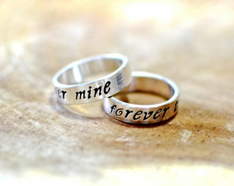 May include: Two silver rings with the words "forever" and "mine" engraved on them.