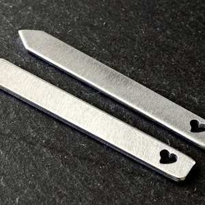 May include: Two silver metal tie bars with a heart cut-out design.