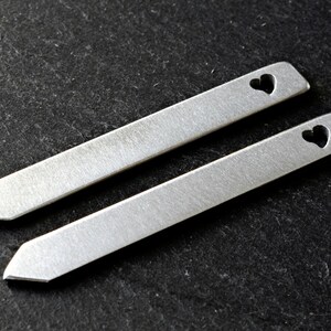May include: Two silver metal tie bars with a heart cut-out design.