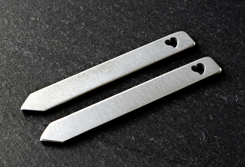 May include: Two silver metal tie bars with a heart cut-out design.