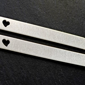 Puede incluir: Dos pasadores de corbata plateados con un dise&ntilde;o de coraz&oacute;n recortado. Los pasadores son lisos y tienen un acabado cepillado.