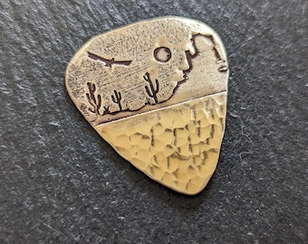 Bronze guitar pick with saguaro cactus and mountains - southwestern theme and playable