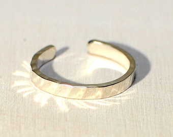 May include: A silver toe ring with a hammered texture. The ring is open and adjustable.
