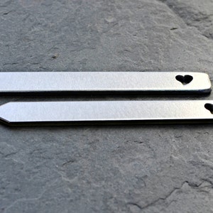 May include: Two silver metal plant markers with a heart-shaped cutout. The markers are approximately 4 inches long.