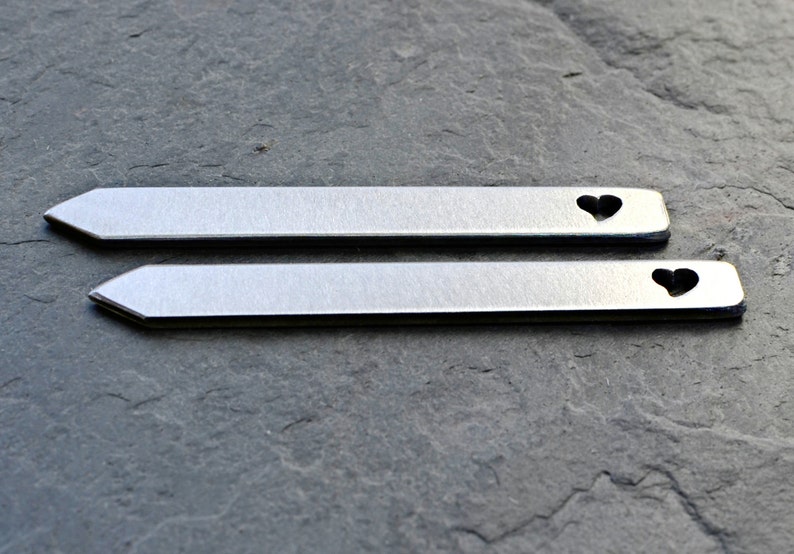 May include: Two silver metal plant markers with a heart-shaped cutout. The markers are approximately 4 inches long.