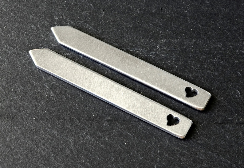May include: Two silver tie bars with a heart cut-out design.