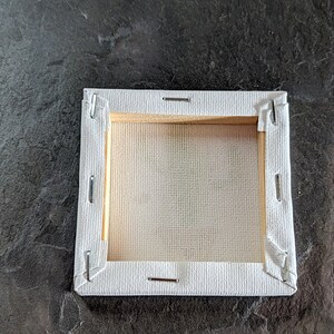 Puede incluir: Un lienzo blanco estirado sobre un marco de madera, listo para pintar. El lienzo est&aacute; asegurado con grapas en los bordes.
