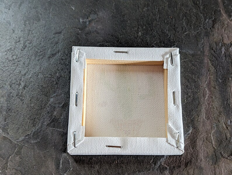 Puede incluir: Un lienzo blanco estirado sobre un marco de madera, listo para pintar. El lienzo est&aacute; asegurado con grapas en los bordes.
