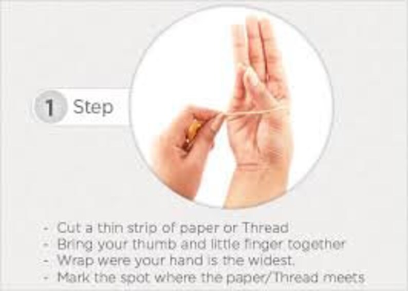 May include: A hand with a thin strip of paper or thread wrapped around it. The paper or thread is wrapped around the hand where it is the widest. The thumb and little finger are touching. The paper or thread is marked where it meets.