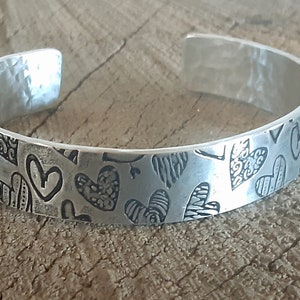 zilveren manchetarmband met hartjes en gehamerde textuur aan de binnenkant - aluminium - licht van gewicht