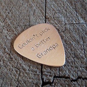 Bronze guitar pick with the text "Couldn't pick a better Grandpa" engraved on it.