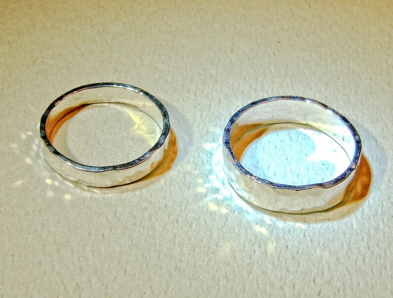 Puede incluir: Dos anillos de plata con textura martillada. Los anillos est&aacute;n sobre una superficie de color marr&oacute;n claro.