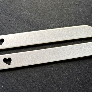 Puede incluir: Dos soportes de cuello de metal plateado con un corte en forma de coraz&oacute;n. Los soportes de cuello miden aproximadamente 5 cm de largo.